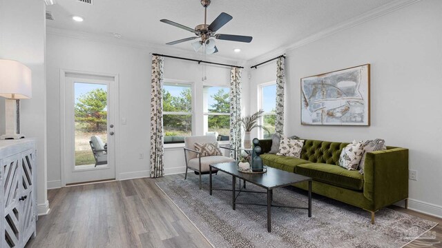 living room with baseboards, ornamental molding, wood finished floors, and a ceiling fan