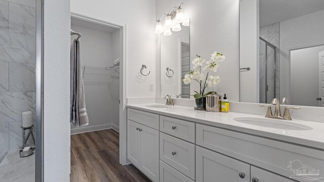 full bathroom with a shower stall, double vanity, wood finished floors, and a sink