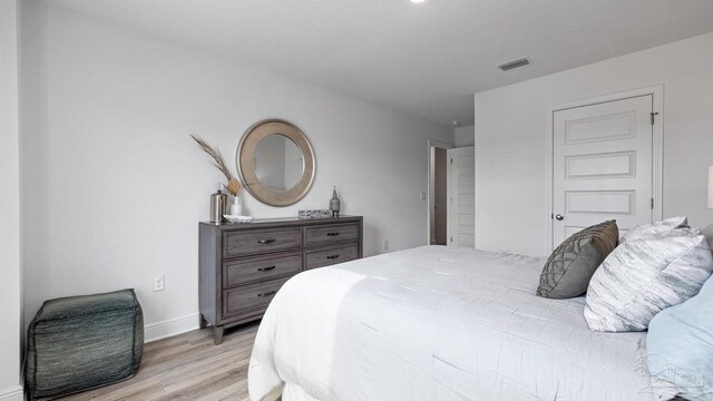 bedroom featuring light wood finished floors, baseboards, and visible vents