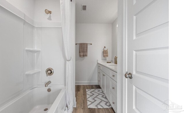 full bathroom featuring vanity, shower / bath combo, wood finished floors, a textured ceiling, and visible vents