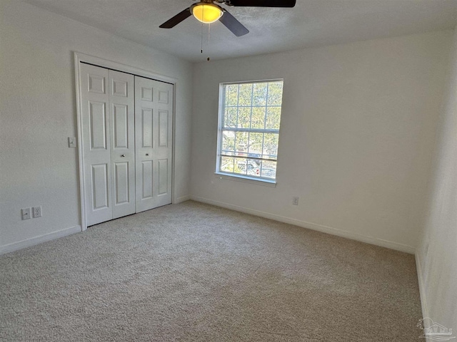 unfurnished bedroom featuring ceiling fan, light colored carpet, and a closet