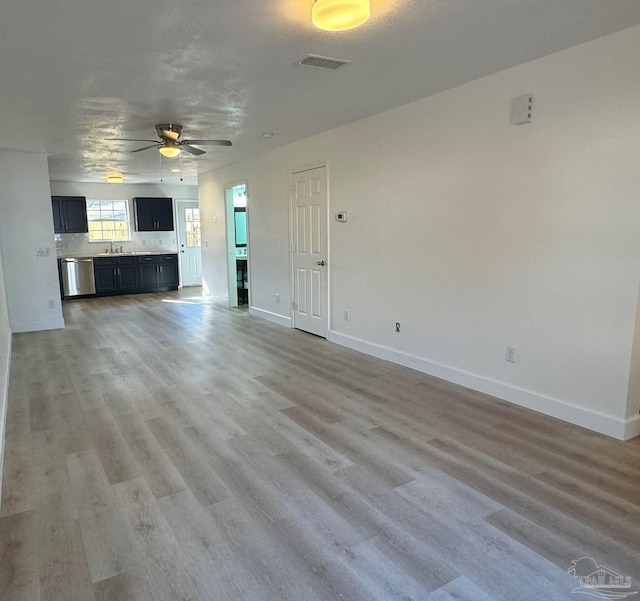 unfurnished living room featuring wood-type flooring, a textured ceiling, ceiling fan, and sink