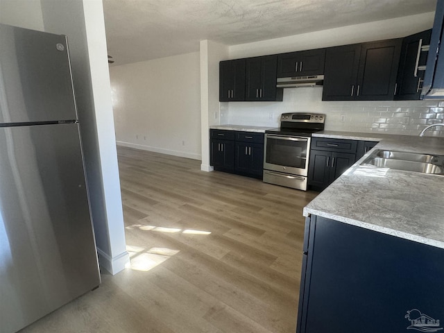 kitchen with stainless steel appliances, light hardwood / wood-style flooring, tasteful backsplash, and sink