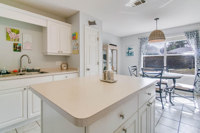 kitchen with sink, white cabinetry, a center island, a textured ceiling, and decorative light fixtures