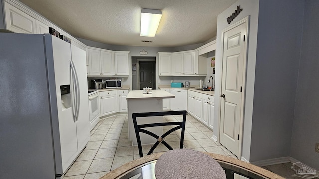 kitchen with a kitchen island, white cabinetry, sink, light tile patterned floors, and white appliances