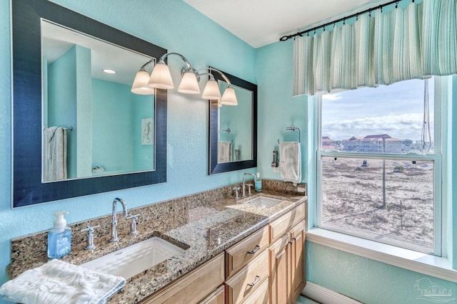 full bath featuring double vanity, baseboards, and a sink