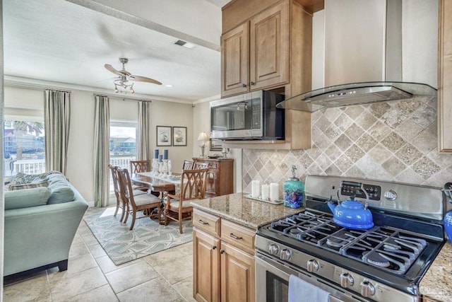 kitchen featuring visible vents, wall chimney range hood, ornamental molding, light stone counters, and appliances with stainless steel finishes