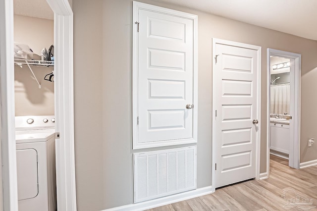 washroom featuring sink, light hardwood / wood-style flooring, and washer / dryer