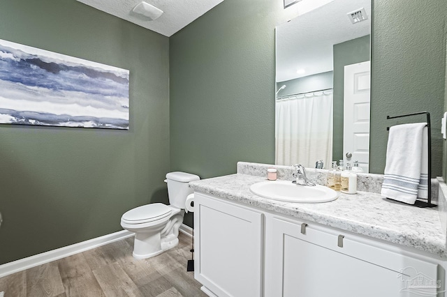 bathroom featuring toilet, vanity, a textured ceiling, and hardwood / wood-style flooring