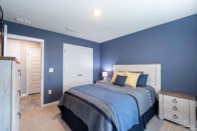 bedroom featuring light carpet, a closet, and a textured ceiling