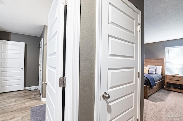 hall featuring light hardwood / wood-style flooring and a textured ceiling