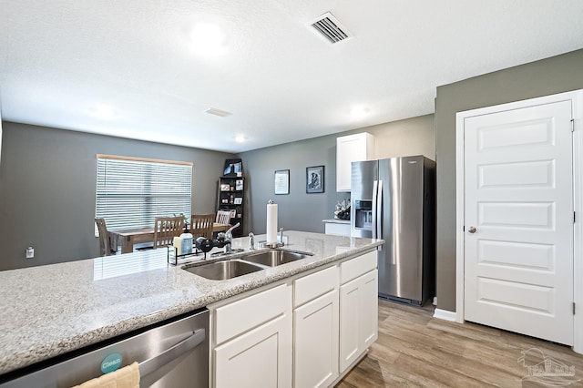 kitchen featuring white cabinetry, light hardwood / wood-style floors, light stone counters, and appliances with stainless steel finishes