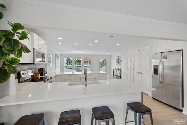 kitchen with sink, stainless steel appliances, a kitchen breakfast bar, kitchen peninsula, and white cabinets