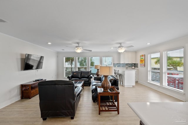 living room featuring light hardwood / wood-style flooring, ceiling fan, and a healthy amount of sunlight