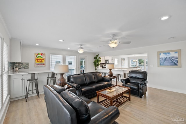 living room with crown molding, ceiling fan, and light hardwood / wood-style floors