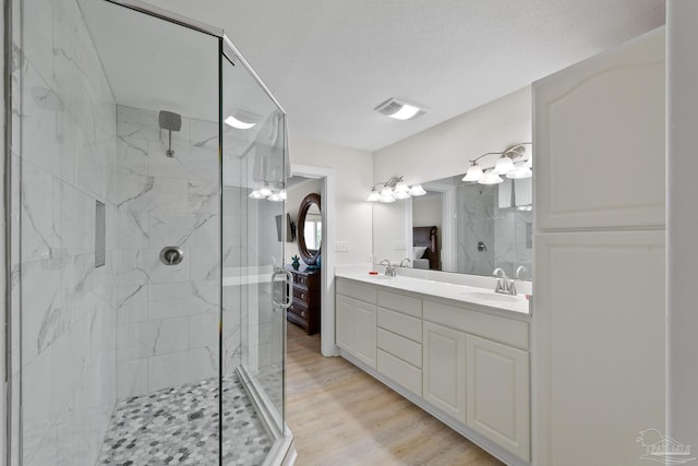 bathroom featuring vanity, wood-type flooring, a textured ceiling, and walk in shower