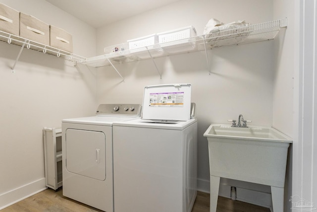 laundry area with independent washer and dryer, sink, and hardwood / wood-style floors