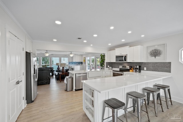 kitchen featuring a breakfast bar, sink, kitchen peninsula, white cabinetry, and stainless steel appliances