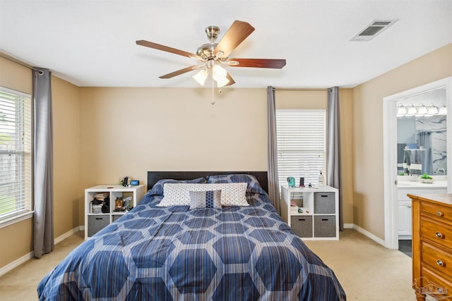 bedroom with ceiling fan, light carpet, and connected bathroom