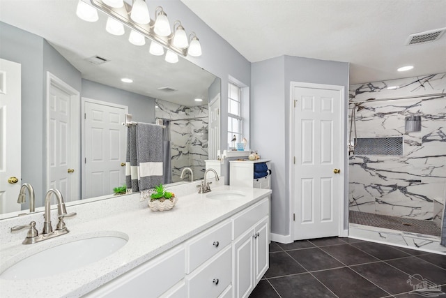 bathroom with tile patterned floors, vanity, and a tile shower