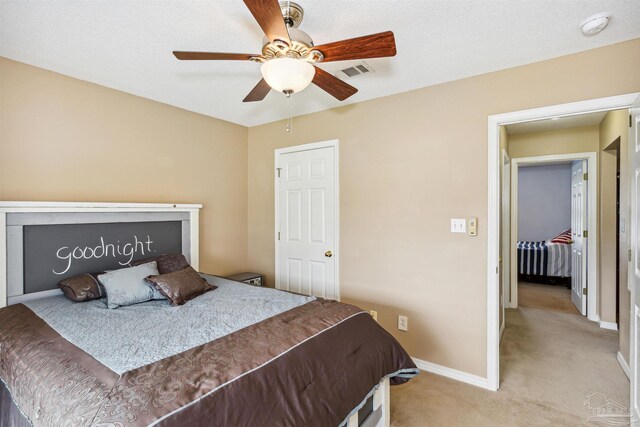 bedroom with light carpet, ceiling fan, and a textured ceiling