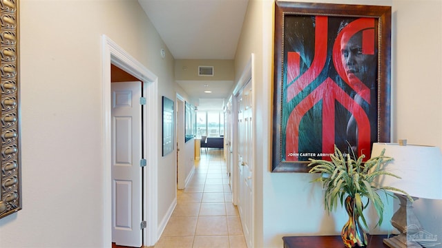 corridor featuring visible vents, baseboards, and light tile patterned flooring