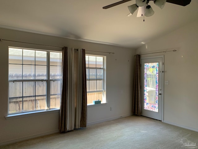 empty room with lofted ceiling, light colored carpet, and ceiling fan