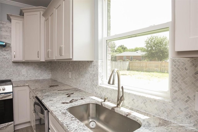 kitchen featuring white cabinetry, light stone countertops, sink, tasteful backsplash, and appliances with stainless steel finishes