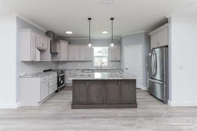 kitchen featuring wall chimney exhaust hood, light stone counters, light hardwood / wood-style flooring, a kitchen island, and appliances with stainless steel finishes