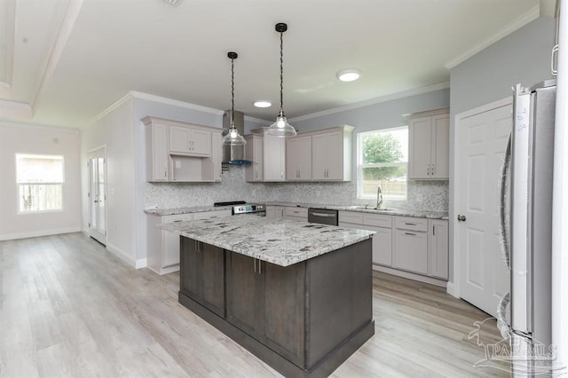 kitchen featuring a center island, ornamental molding, appliances with stainless steel finishes, light hardwood / wood-style floors, and light stone counters