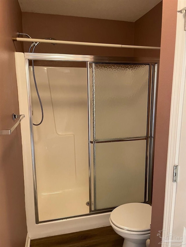 bathroom featuring walk in shower, toilet, and hardwood / wood-style flooring