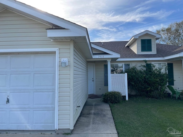 doorway to property featuring a garage and a lawn