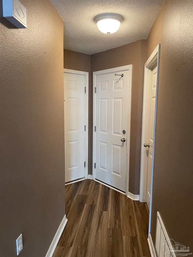 hallway with dark wood-type flooring and a textured ceiling