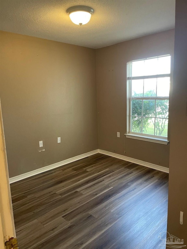 empty room with dark hardwood / wood-style floors and a textured ceiling