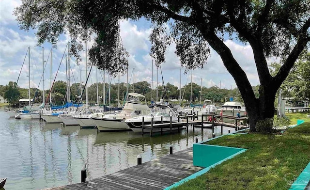 view of dock with a lawn and a water view