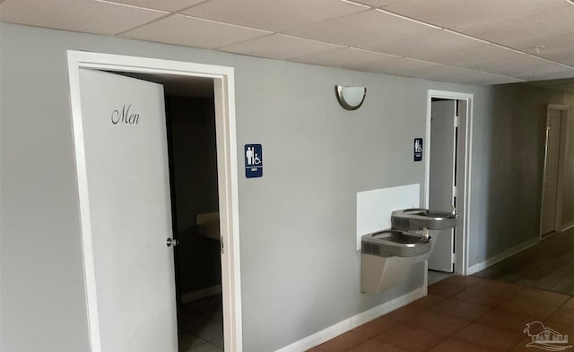 hall with a drop ceiling and dark tile patterned flooring