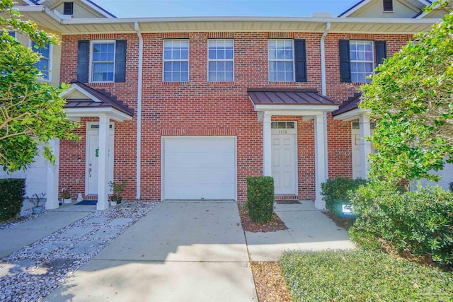 multi unit property featuring an attached garage, a standing seam roof, concrete driveway, and brick siding