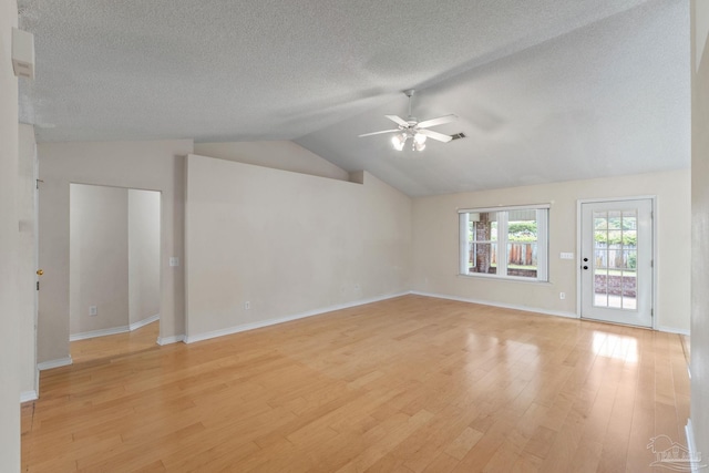 unfurnished living room featuring light wood-style flooring, a ceiling fan, a textured ceiling, baseboards, and vaulted ceiling