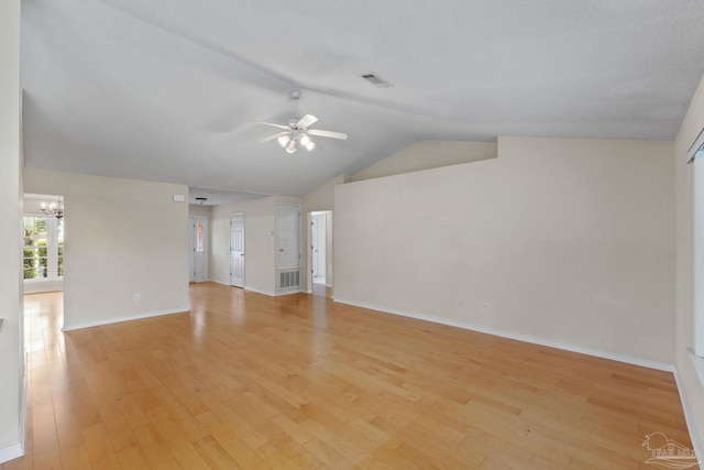 unfurnished living room with vaulted ceiling, visible vents, light wood finished floors, and ceiling fan with notable chandelier