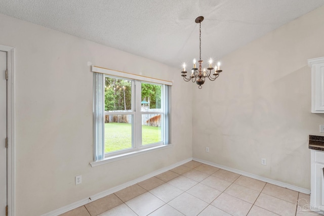 unfurnished dining area featuring an inviting chandelier, light tile patterned floors, and a healthy amount of sunlight