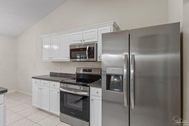 kitchen featuring white cabinets, stainless steel appliances, light tile patterned flooring, and lofted ceiling