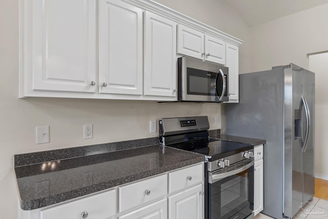 kitchen with dark countertops, appliances with stainless steel finishes, baseboards, and white cabinetry