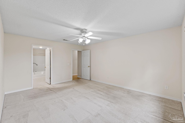 unfurnished bedroom with carpet, a textured ceiling, visible vents, baseboards, and ensuite bath