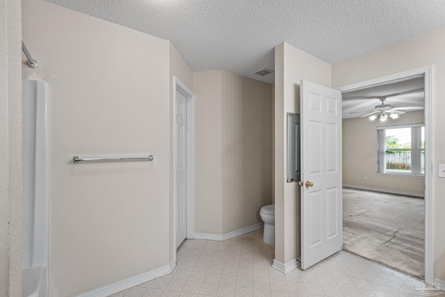 bathroom featuring toilet, a ceiling fan, a textured ceiling, visible vents, and baseboards