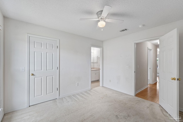 unfurnished bedroom featuring a textured ceiling, baseboards, visible vents, and carpet