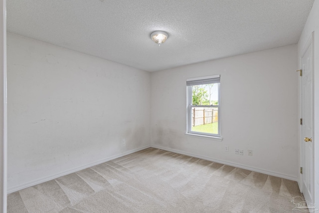 spare room with a textured ceiling, carpet floors, and baseboards