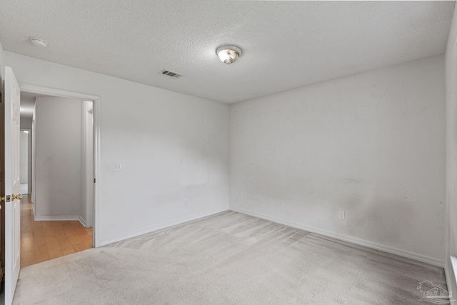empty room with a textured ceiling, visible vents, baseboards, and carpet floors