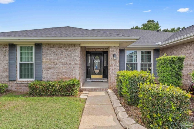 property entrance featuring roof with shingles and brick siding