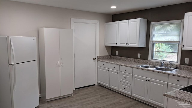 kitchen with sink, white refrigerator, white cabinets, and light wood-type flooring