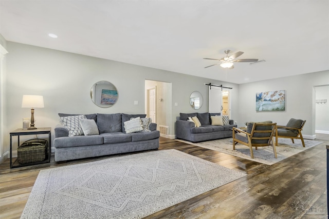 living room featuring ceiling fan, a barn door, and hardwood / wood-style floors